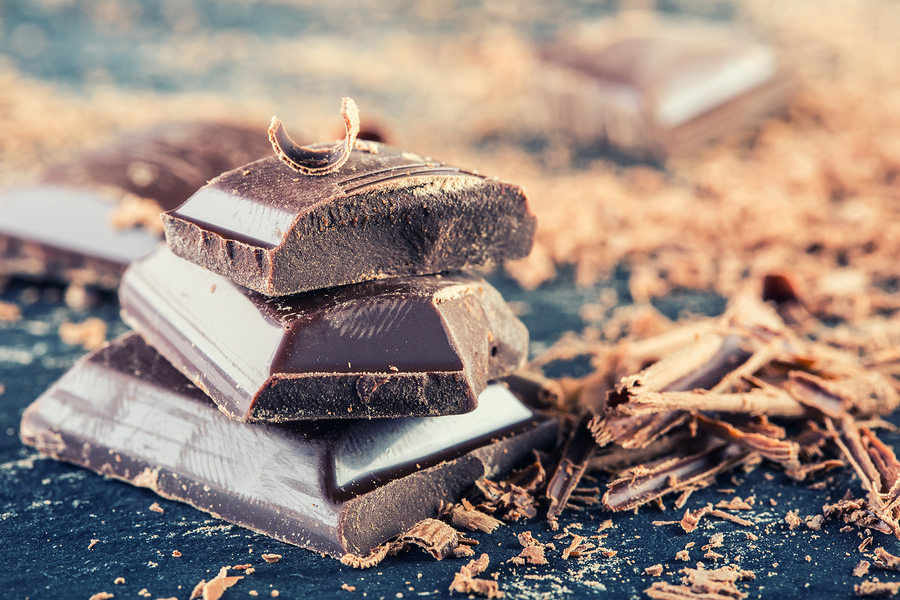 Chocolate. Black chocolate. A few cubes of black chocolate with mint leaves. Chocolate slabs spilled from grated chockolate powder.