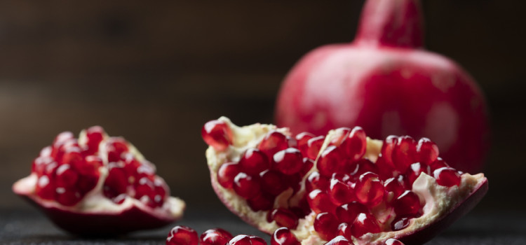 pomegranate that has cut open on black wooden background